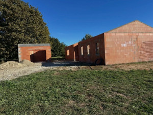 Photo de galerie - Maison en cours de construction, avec des murs en briques rouges, un garage indépendant et un terrain encore en aménagement.