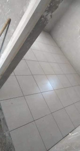 Photo de galerie - Pose de carrelage au sol avec des carreaux blancs soigneusement alignés.