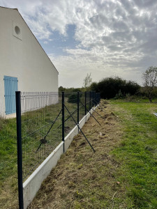 Photo de galerie - Pose de clôture rigide avec soubassement béton  Réalisation d’une clôture rigide avec panneaux grillagés noirs et soubassements en béton, pour délimiter et sécuriser le terrain tout en gardant une finition propre et moderne.