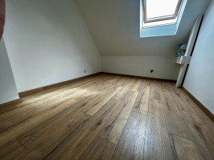 Photo de galerie - Pose d’un parquet stratifié avec sa sous-couche et ses plinthes assorties pour un rendu chaleureux.
