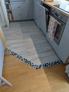 Photo de galerie - Pose de parquet stratifié gris + frise en faïence pour le raccord au parquet existant 