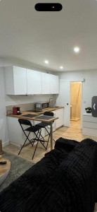 Photo de galerie - Cuisine moderne et fonctionnelle, idéale pour petit espace. Installation propre avec meubles hauts et bas, plan de travail bois, évier avec robinetterie, plaque de cuisson et coin repas intégré. Finition soignée