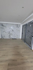 Photo de galerie - Carrelage  au mur et Carrelage  effets  parquet  au sol de un salon 