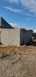 Photo de galerie - Extension en parpaings réalisée en maçonnerie traditionnelle. Montage des murs sur dalle existante avec alignement et niveaux parfaitement respectés. Chaînages et réservations intégrés pour la future toiture.