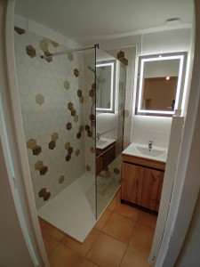 Photo de galerie - Dépose des anciens éléments sanitaires et création d'une nouvelle douche avec panneaux muaux et miroir avec meuble vasque 
