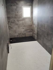 Photo de galerie - Rénovation d'une salle de bain, avec pose de dalles murales PVC design sur 2 coloris ( gris clair, côté douche)
Pose du bac à douche en résine noir
pose dalle de parquet PVC blanc marbré
