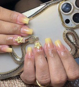 Photo de galerie - Pose d'ongles en gel avec un magnifique dégradé Ombré jaune. Finition élégante avec des fleurs en 3D pour une touche de fantaisie printanière. Tenue longue durée et brillance garantie.