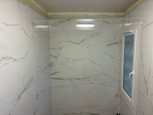 Photo de galerie - Préparation et remise à niveau des murs, rebouchage des imperfections, application d’un primaire d’accrochage et pose soignée de carrelage grand format 120 × 60 cm, effet marbre.