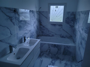 Photo de galerie - Pose de grands carreaux au sol et sur les murs d'une salle de bain avec baignoire