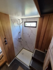 Photo de galerie - Conception d'une douche dans un motorhome. 
Revêtement PVC imitation marbre et habillage mural en placage Red Cedar vernis marin trois couches.
Plafond en toile de verre 160gr/m² laqué deux couches.