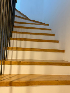Photo de galerie - Rénovation complète d'un escalier encrassé par les graisses et l'usure. Après un dégraissage et ponçage intensif, le bois retrouve tout son éclat. Résultat : un aspect moderne et propre avec une finition vernie et blanche.