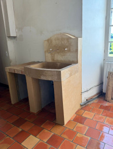 Photo de galerie - Création artisanale d’un évier avec bac en pierre naturelle, plan de travail carrelé, jambages en briques et finition à l’enduit de chaux.