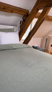 Photo de galerie - Chambre préparée avec soin : lit impeccable, ambiance chaleureuse et poutres pleines de charme