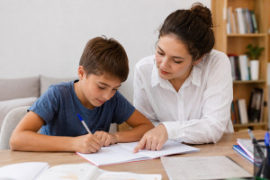 Photo de galerie - Une baby-sitter accompagne un enfant pendant ses devoirs dans une ambiance calme et chaleureuse. 