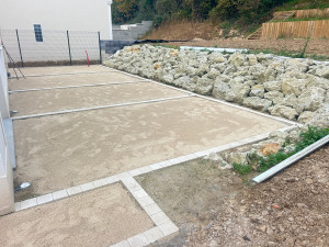 Photo de galerie - Terrassement avec préparation pour terrasse avec enrochement et chaînette pavés 