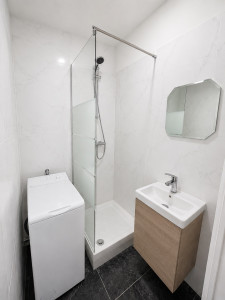 Photo de galerie - Installation d'un bac à douche avec paroi vitrée, d'un lave-mains avec meuble suspendu et raccordement d'une machine à laver dans une salle d'eau moderne.