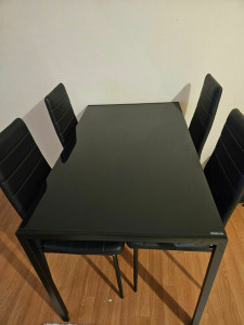 Photo de galerie - Montage de chaises et d'une table de salle à manger avec plateau en verre noir