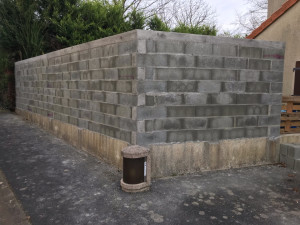 Photo de galerie - Remplacement de poteaux bois et de claustras bois par un mur de clôture en parpaings, pose des armatures, coulage des poteaux et de l’arase béton.