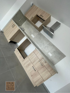 Photo de galerie - ? Cuisine sur mesure installée Réalisation d’un agencement de cuisine moderne avec meubles en bois clair et plan de travail effet béton.