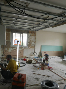 Photo de galerie - Travaux de rénovation intérieure en cours : préparation du plafond avec installation de l’ossature métallique, passage des câbles et préparation des surfaces. Dépose et remise en état des murs, préparation avant pose des plaques et finitions.