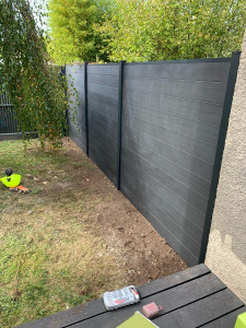 Photo de galerie - Remplacement d’un ancien grillage souple par une clôture moderne et robuste en lames composite anthracite.