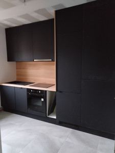 Photo de galerie - Une cuisine complètement équipée, fabriqué en noir mate avec un plan de travail, crédence et une joue en hêtre.