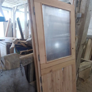 Photo de galerie - Porte d'entrée d'une yourte en merisier et fenêtre en plexiglass (pour éviter la casse du verre avec les déformation de la structure)