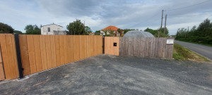 Photo de galerie - Réalisation d'un portail coulissant  mesure en acier thermolaqué avec habillage bois et avec motorisation BFT et interphone.
