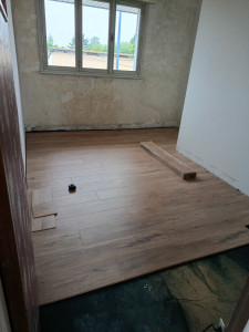 Photo de galerie - Pose du parquet en cours, avec ajustement et assemblage des lames dans la pièce.