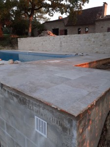 Photo de galerie - Plage de piscine avec pose de travertin , et bâtisse d'un mur en pierre.