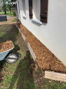 Photo de galerie - Garnison d’un parterre de fleur avec des copeaux de bois et mise en place de petites barrières.