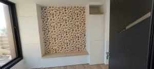 Photo de galerie - Création sur mesure sur tout un pent de mir de rangements avec banquette relevable pour optimiser au maximum l'espace dans une toute petite maison.