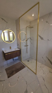 Photo de galerie - Réalisation complète d’une salle de bain : installation de la plomberie et des équipements sanitaires, pose du meuble vasque, robinetterie et installation de la douche avec receveur et paroi. Une finition soignée pour une salle de bain moderne et fonction