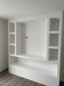 Photo de galerie - Réalisation d'un meuble TV design et sur mesure en plaques de plâtre (Placo) avec niches de rangement intégrées et emplacements pour spots encastrés.