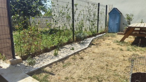 Photo de galerie - Création d'un pourtour de plantes en gravier. Mise en œuvre d'une bordure de délimitation, pose de géotextile et finition minérale pour un jardin propre et structuré.
