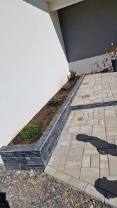 Photo de galerie - Création d'un bac à fleurs en agglo, pose de pavés avec marche et finition avec un parement en ardoise. 