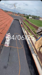 Photo de galerie - Réalisation de l’étanchéité bitumineuse bicouche sur toiture en OSB, avec soudure des membranes au chalumeau et préparation des relevés d’étanchéité avant la pose du Paxalu (bitume autoprotégé aluminium
