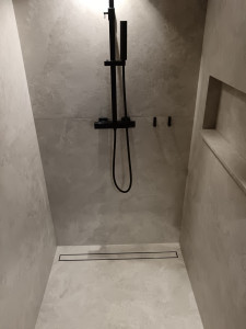 Photo de galerie - Réalisation d'une douche avec du carrelage grand format, bac à douche forme de pente et caniveau, niche dans le mur avec une tablette tout carrelage biseauté