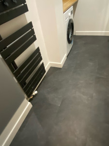 Photo de galerie - Après la réalisation de la chape, travaux de finition : pose de stratifié noir dans la salle de bain et installation des plinthes.