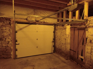 Photo de galerie - Réalisation d'une pose de porte de garage sectionnelle motorisée en gris anthracite. Installation d'un modèle moderne et automatisé, avec réglages pour un confort optimal au quotidien. Travail soigné et précis.