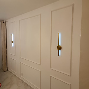 Photo de galerie - Installation de moulures décoratives et luminaires sur un mur d'un séjour 