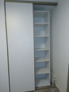 Photo de galerie - Pose d'un aménagement de placard avec rayonnages et penderie, intégré derrière des portes coulissantes existantes pour optimiser l'espace
