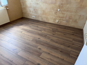 Photo de galerie - Pose de sol stratifié effet bois dans une chambre.
Travail soigné pour un rendu chaleureux et moderne, avec finitions propres en plinthes assorties.
