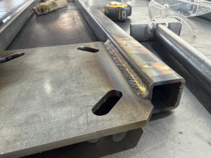 Photo de galerie - Soudure propre et régulière sur tube carré en acier, assemblé à une platine découpée. Cordons uniformes, bonne pénétration et finition soignée pour un support solide et durable.