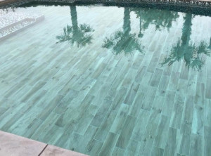 Photo de galerie - Réalisation d’une piscine avec pose de carrelage, finition soignée et revêtement intérieur en carrelage imitation bois.