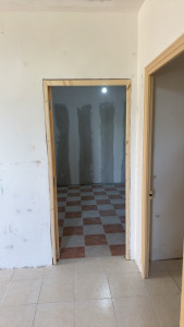 Photo de galerie - Pose d’un bloc-porte intérieur avec réglage, fixation du dormant, pose de la porte, habillage bois de l’ouverture et reprises ponctuelles des supports autour du bâti.