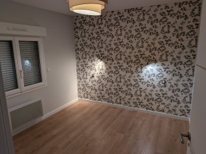 Photo de galerie - Travaux de rénovation d'une chambre, incluant mise en peinture, pose de papier-peint et pose de parquet avec plinthes.