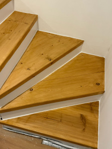 Photo de galerie - Rénovation complète d'un escalier encrassé par les graisses et l'usure. Après un dégraissage et ponçage intensif, le bois retrouve tout son éclat. Résultat : un aspect moderne et propre avec une finition vernie et blanche.