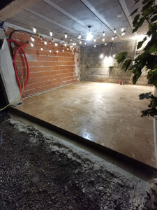 Photo de galerie - Création d'une dalle béton dans une cave sous un parking et pose d'un sol en pierre naturelle polie pour l'emménagement d'une cuisine extérieure.  