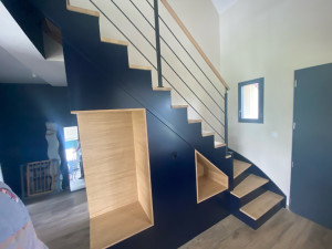 Photo de galerie - Réalisation d’un escalier contemporain en bleu nuit mat, sublimé par des marches et niches en chêne naturel. Un contraste sobre et élégant qui apporte du caractère à l’entrée tout en conservant une ambiance chaleureuse.